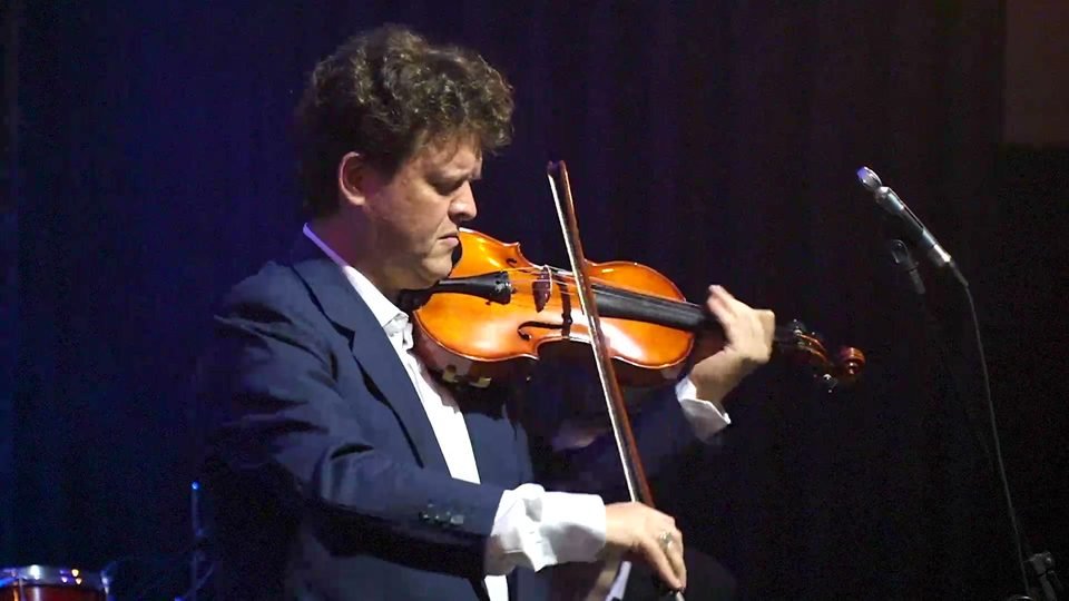 Roney Marczak toca violino com o arco erguido.